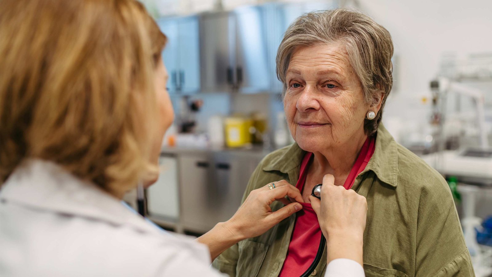 Clinician with a stethoscope examining an older adult Medicare patient during a chronic care consultation