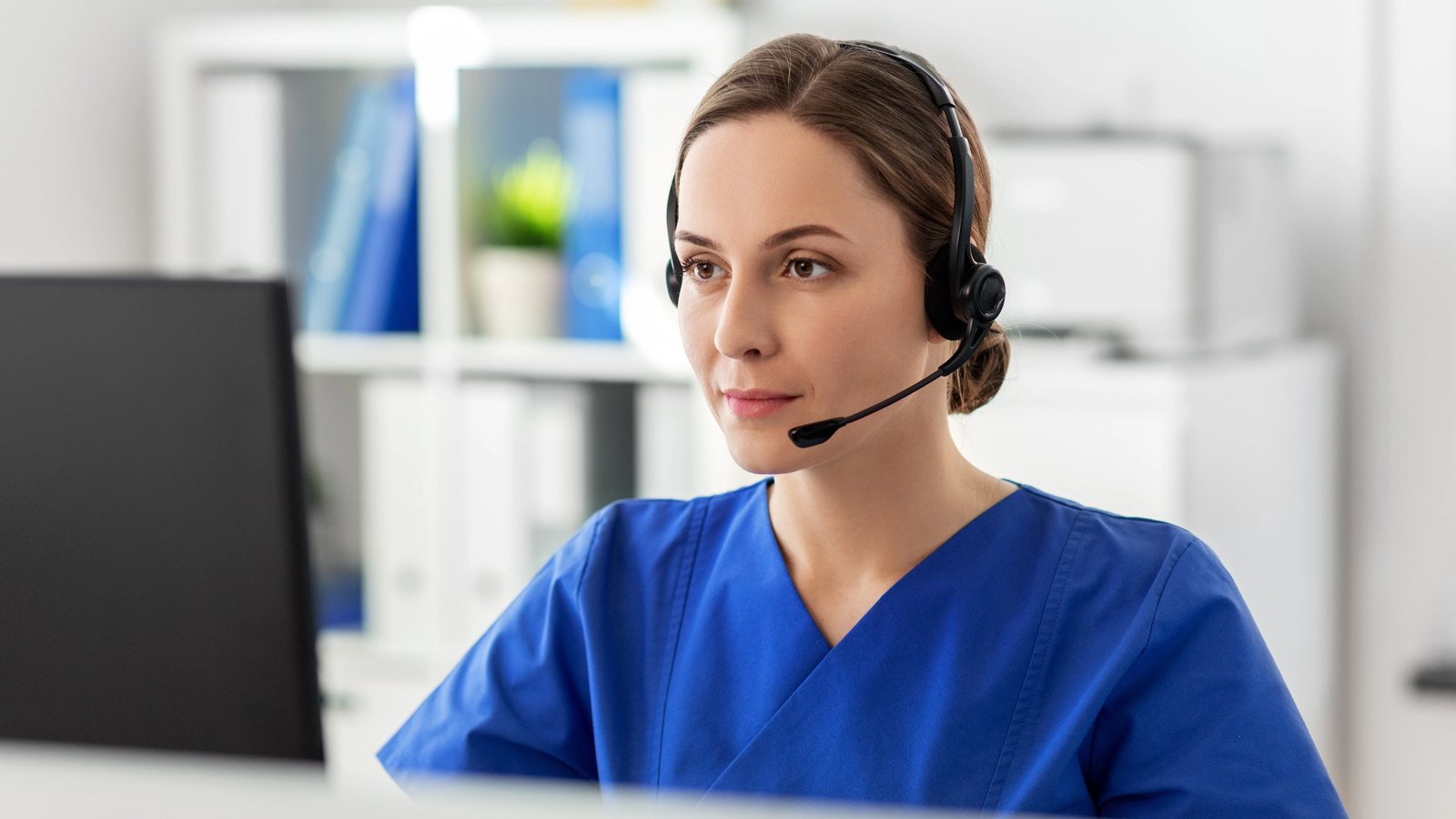 Care coordinator wearing a headset making a monthly patient check-in call at a computer workstation